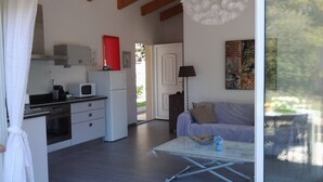 Una cucina moderna con elettrodomestici bianchi, una zona pranzo con tavolo in vetro e un soggiorno con divano e un quadro.