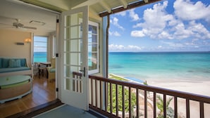 A room with a balcony overlooking a beach, a ceiling fan, a sofa, and a dining area. - Santosha Villa Estate, Private Staffed Beach Resort All to Yourself, Sleeps 21 (Long Bay Village)