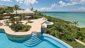 A resort with a swimming pool, outdoor seating, and a view of the ocean. - Santosha Villa Estate, Private Staffed Beach Resort All to Yourself, Sleeps 21 (Long Bay Village)