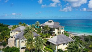 A resort with multiple buildings, a beach, and a clear blue sky. - Santosha Villa Estate, Private Staffed Beach Resort All to Yourself, Sleeps 21 (Long Bay Village)