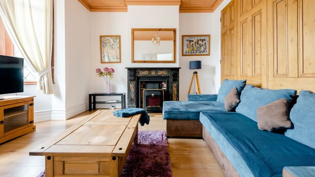 A living room with a fireplace, a television, a sofa, and a wooden cabinet. - Cyrus House Dartford Centre (Dartford)