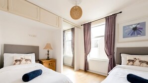 A hotel room with two beds, a nightstand with a lamp, and a window with curtains. - Cyrus House Dartford Centre (Dartford)