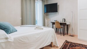 A bedroom with a bed, a desk, a chair, a television, and a door.