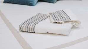A neatly made bed with a striped towel and two pillows.