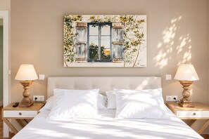 A bedroom with a bed, two bedside tables, two lamps, and a painting on the wall. - Finca Aprisco de Candeleda, a dream to share. (candeleda)