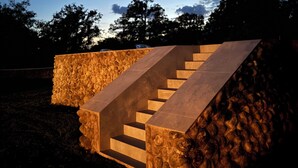 A staircase with a stone wall on one side and a clear sky with clouds and a moon in the background.