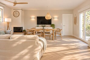 A modern living room with a sofa, dining table, chairs, a TV, and a fireplace. - Finca Aprisco de Candeleda, a dream to share. (candeleda)