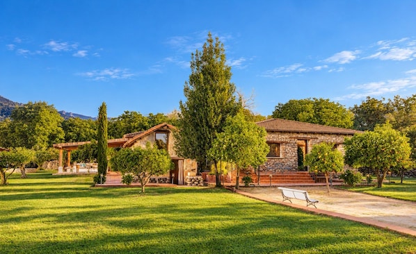 A stone building with a tiled roof, surrounded by a well-maintained lawn and trees. - Finca Aprisco de Candeleda, a dream to share. (candeleda)