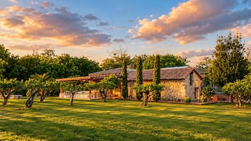 A stone building with a tiled roof, surrounded by a well-maintained lawn and trees.
