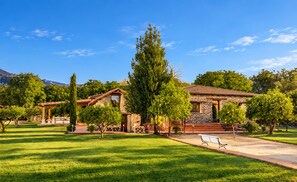 Une propriété résidentielle comprenant une maison en pierre, une pelouse bien entretenue et un ciel dégagé.