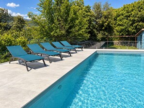 A swimming pool with lounge chairs and a stone wall. - Finca Aprisco de Candeleda, a dream to share. (candeleda)