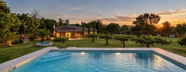 A swimming pool with a stone-lined edge, surrounded by a well-maintained lawn and trees. - Finca Aprisco de Candeleda, a dream to share. (candeleda)