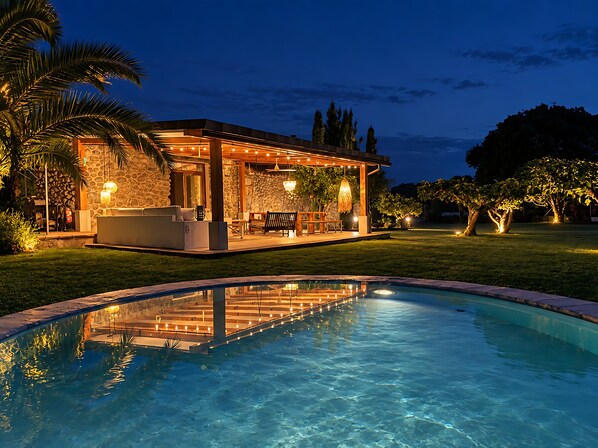 Piscina com área de estar, paredes de pedra e mobiliário de exterior.