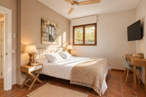 A bedroom with a bed, bedside tables, a desk, a television, a window, and a ceiling fan. - Finca Aprisco de Candeleda, a dream to share. (candeleda)