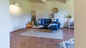 Un salon avec un canapé bleu, une table basse ronde et un tapis à motifs.