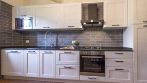Une cuisine moderne avec des meubles blancs, une cuisinière à gaz et un four encastré.