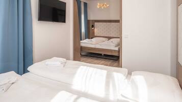 A hotel room with a bed, a TV mounted on the wall, and a chandelier.