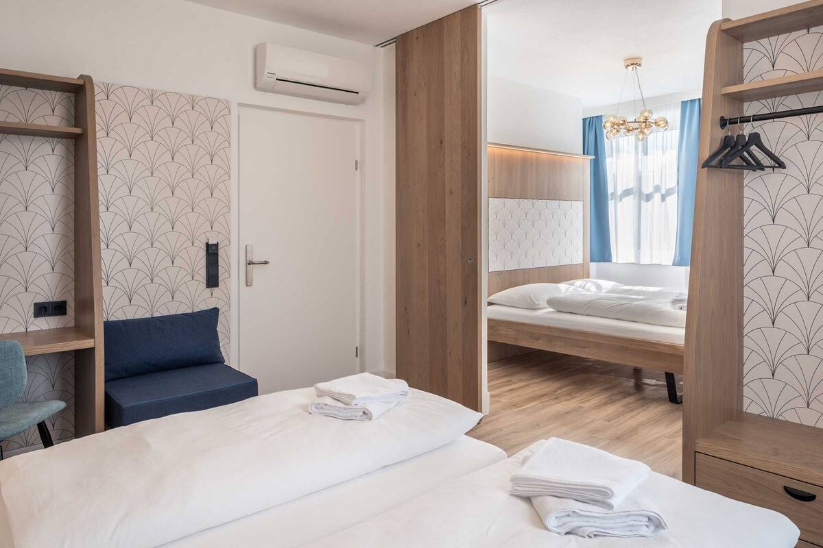 A modern hotel room with a large bed, a desk, and a wardrobe.