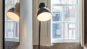 En golvlampa med en reflekterande lampskärm i ett rum med ett stort fönster.