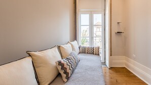 A narrow hallway with a bench, a door leading to an outdoor balcony, and a light switch on the wall. - GuestReady - Modern luxe getaway in Vitória (Porto)