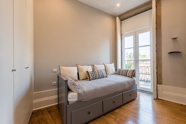 Un dormitorio con cama, radiador, puerta y ventana.