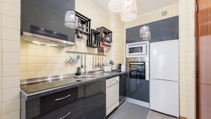 Una cucina moderna con pensili neri, un piano di lavoro in acciaio inossidabile, forno integrato, microonde ed elettrodomestici.