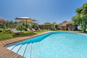 A swimming pool with wooden deck, lounge chairs, and an umbrella. - GuestReady - Sunset Pool House (Esposende)