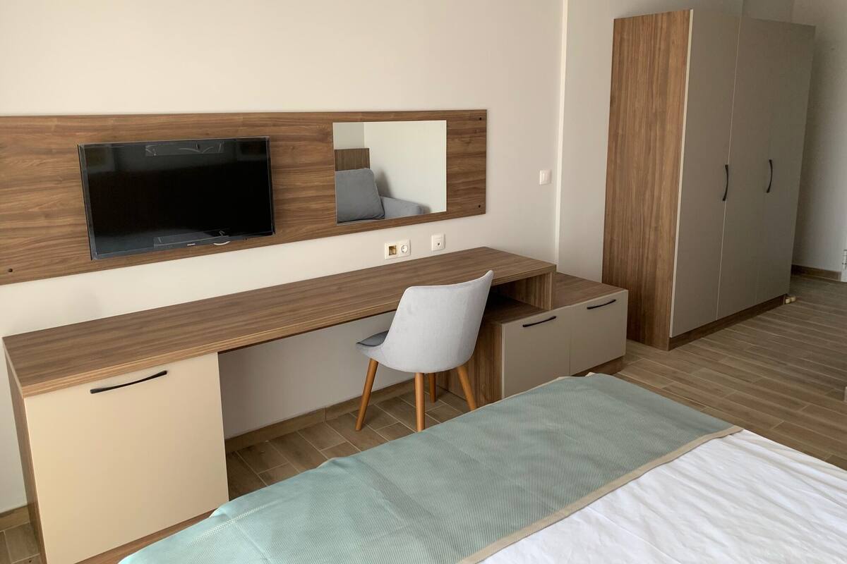 Un dormitorio con cama, escritorio, silla, televisor y armario.