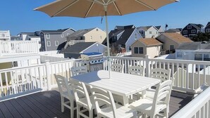 Une terrasse avec une table et des chaises, un parasol et une vue sur les maisons au loin.