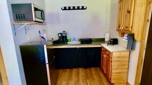 Une cuisine compacte équipée d’un four à micro-ondes, d’une machine à café et d’un évier.
