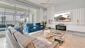 Uma sala de estar moderna com um sofá grande, poltronas azuis, uma mesa de centro e uma TV exibindo 'Fast & Furious 8'.