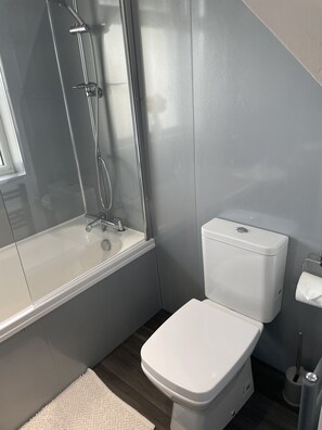 Uma casa de banho moderna com chuveiro, sanita e lavatório.