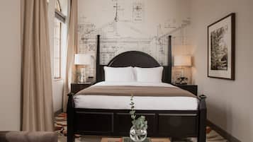 Une chambre avec un grand lit, une carte accrochée au mur, une plante sur la table de chevet et un tableau encadré au mur.