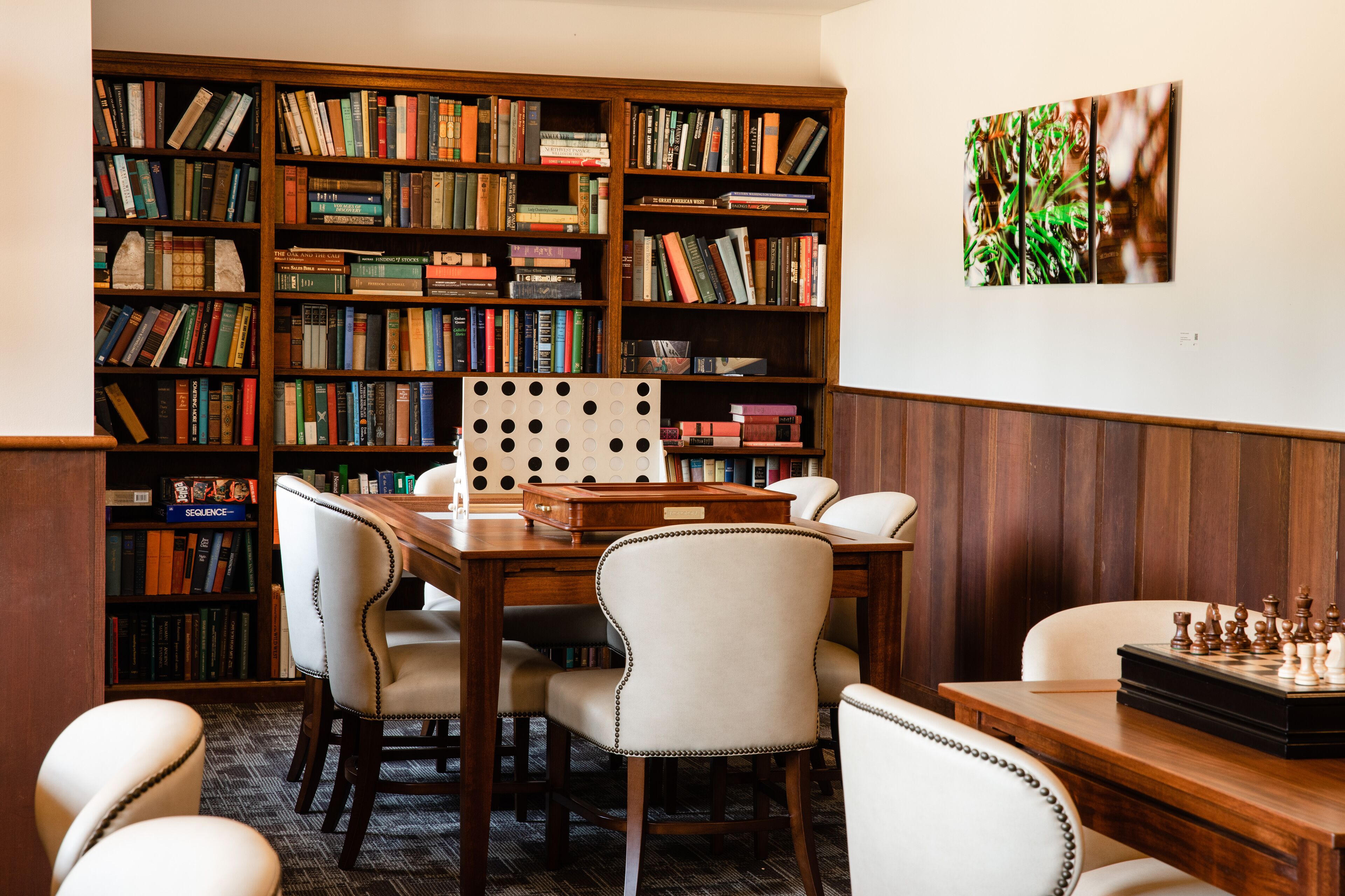Eine Bibliothek mit Bücherregalen, einem Schachbrett und einem Holztisch.