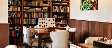 A library with bookshelves, a chess table, and a wooden desk.
