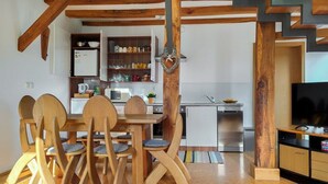 Une cuisine moderne avec des chaises en bois, une table à manger et un téléviseur posé sur un meuble en bois.