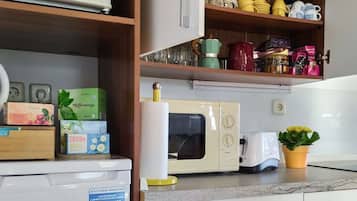 A kitchen with a microwave, toaster, and various kitchen items on shelves.