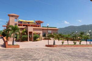 Un hotel con un letrero llamativo, un patio empedrado y palmeras.