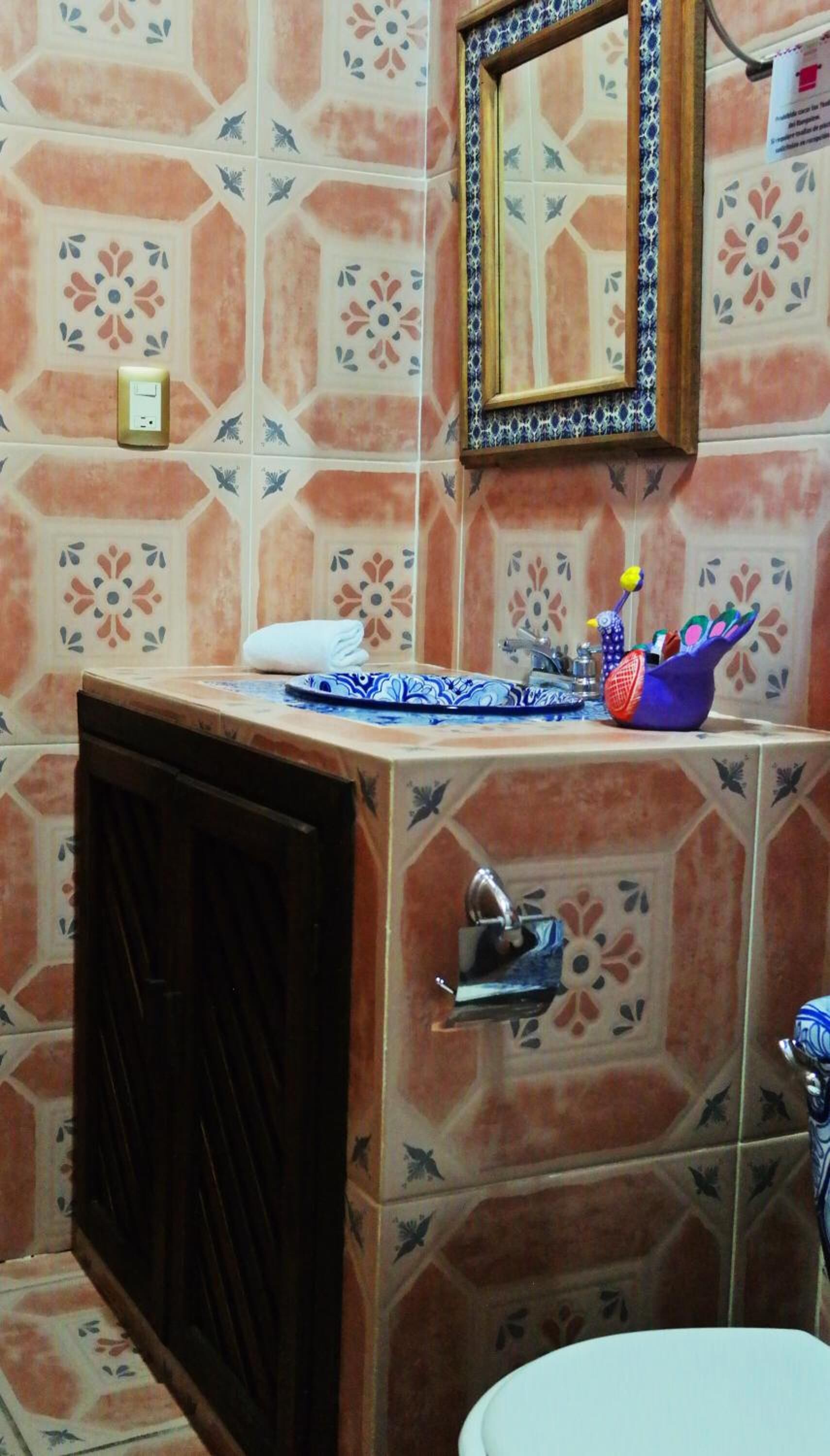 A bathroom with a sink, mirror, and decorative tiles.