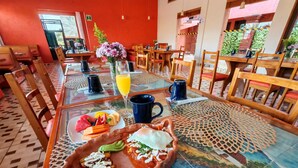 Comedor con mesas dispuestas para el desayuno, incluyendo platos de comida y bebidas.