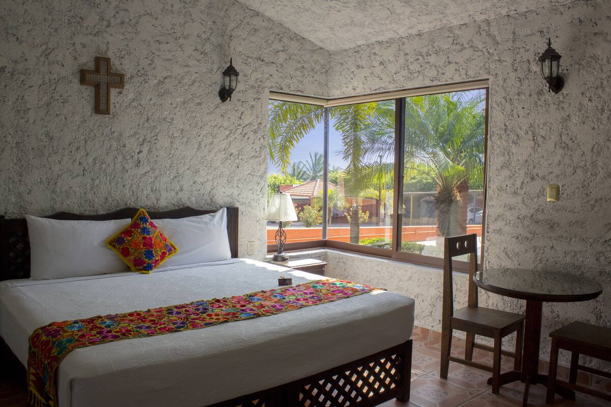 Un dormitorio con una cama grande, una mesita pequeña y una silla.