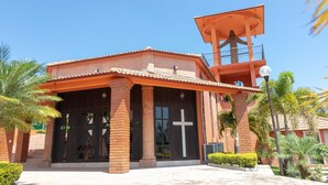 Una iglesia con un campanario, fachada de ladrillo y una cruz en la puerta.