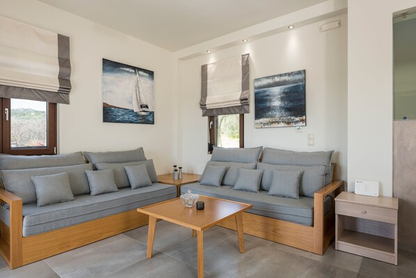 A modern living room with two grey sofas, a wooden coffee table, and artwork on the walls.