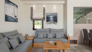Een moderne woonkamer met een grijze bank, een houten salontafel en een schilderij van een zeilboot.