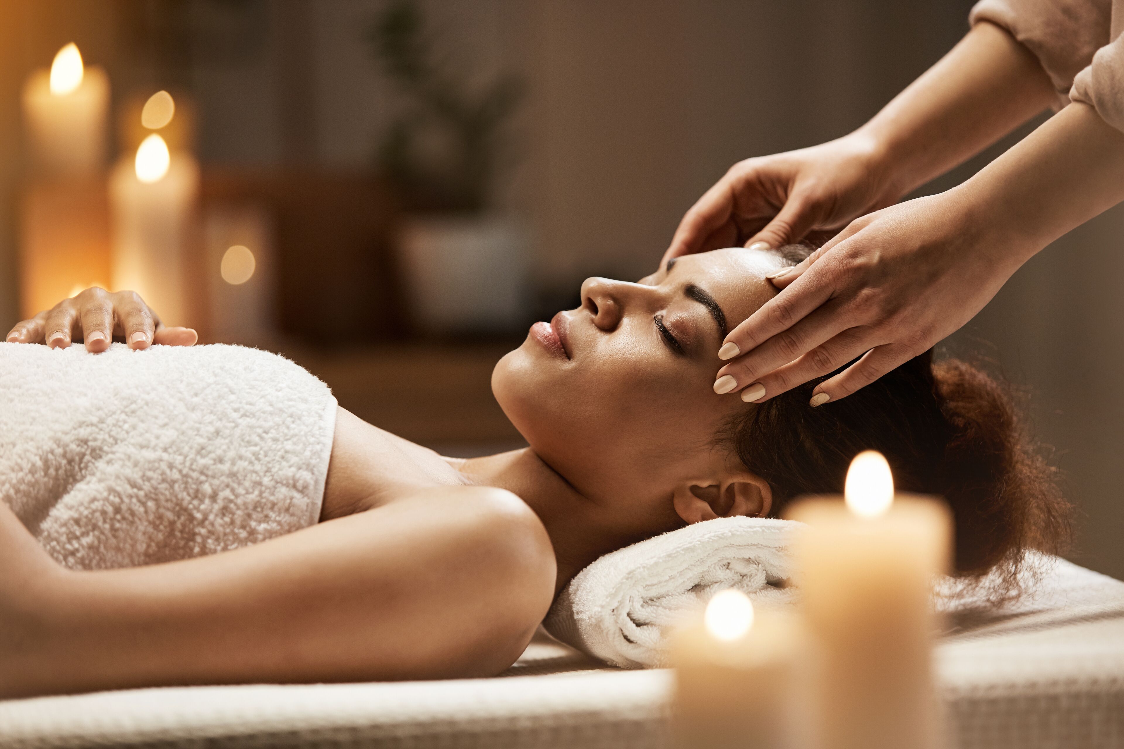 A person receiving a massage with candles in the background.