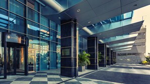 A modern building with a glass facade, a revolving door entrance, and a checkered floor pattern. - Intercontinental Luanda Miramar by IHG (Luanda)