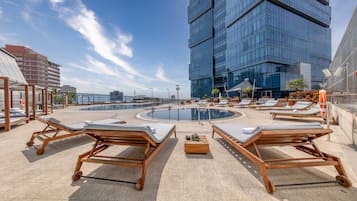 Una piscina al aire libre, sombrillas, sillones reclinables de piscina