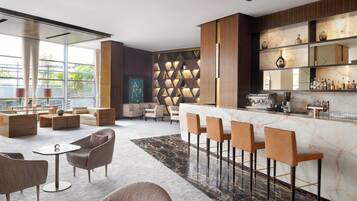 Un moderno bar con asientos, una encimera de mármol y una pared decorativa con patrones geométricos.