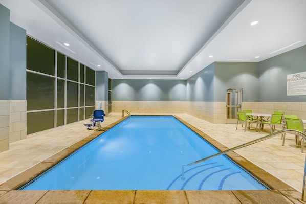 An indoor swimming pool with clear water, surrounded by beige tiled walls and a ceiling with recessed lighting. - Holiday Inn Express & Suites Lincoln Downtown by IHG (Lincoln)