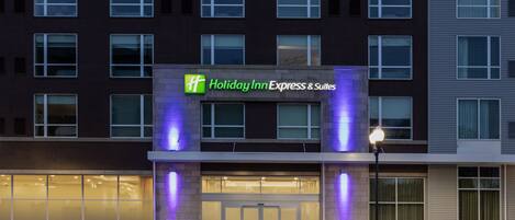 A Holiday Inn Express & Suites building with a modern facade, large windows, and a prominent entrance.